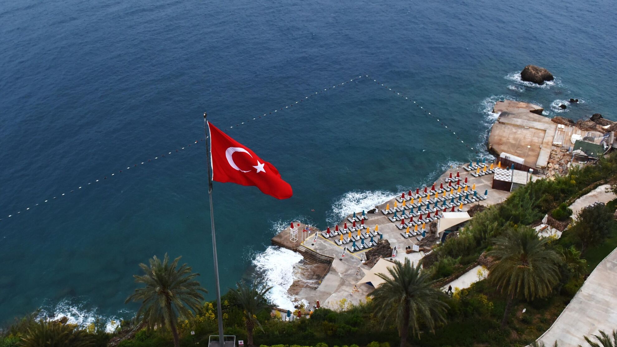 шезлонги на пляже в отеле в Турции с турецким флагом, морем и пальмами - Raketanews.ru, 17.08.2023